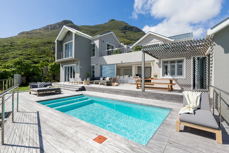 A villa in Cape Town with its pool, open terrace and green mountains behind
